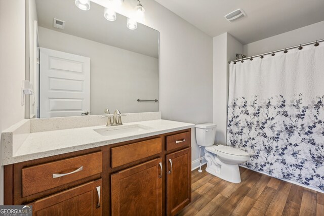 bathroom with toilet, vanity, and hardwood / wood-style floors