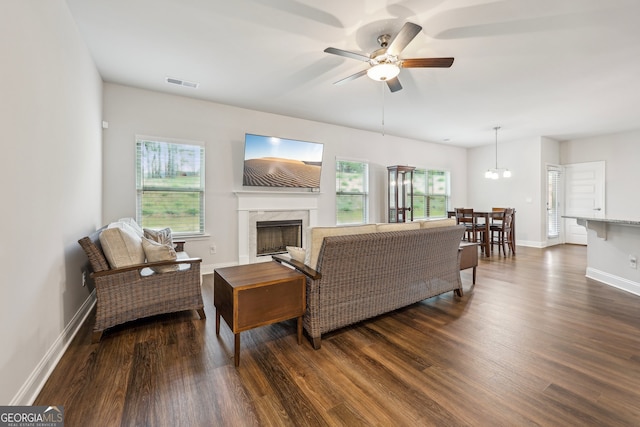 living room featuring dark wood-type flooring, a wealth of natural light, a fireplace, and ceiling fan