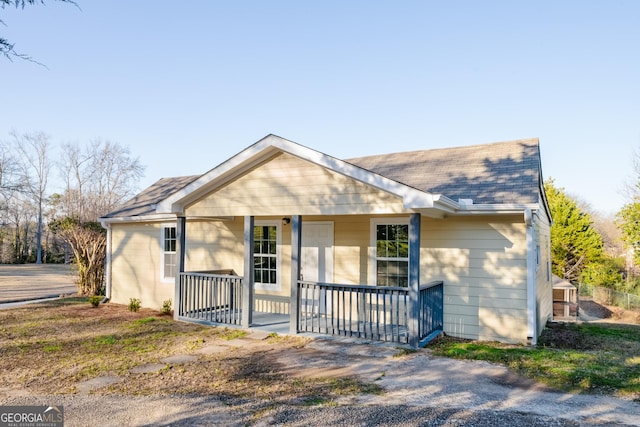 ranch-style home with a porch and roof with shingles