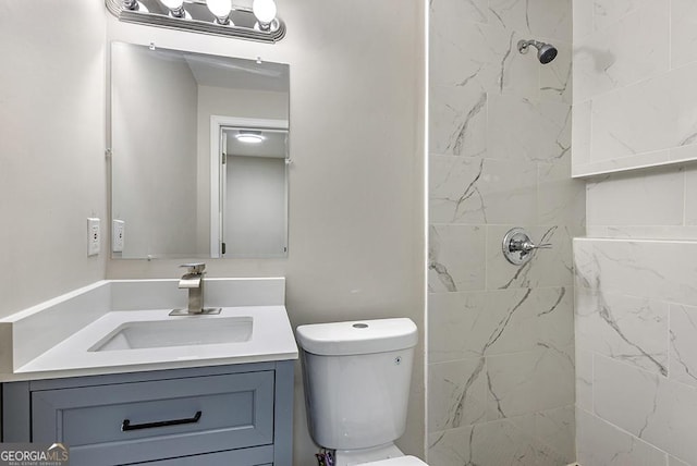 full bathroom with tiled shower, vanity, and toilet