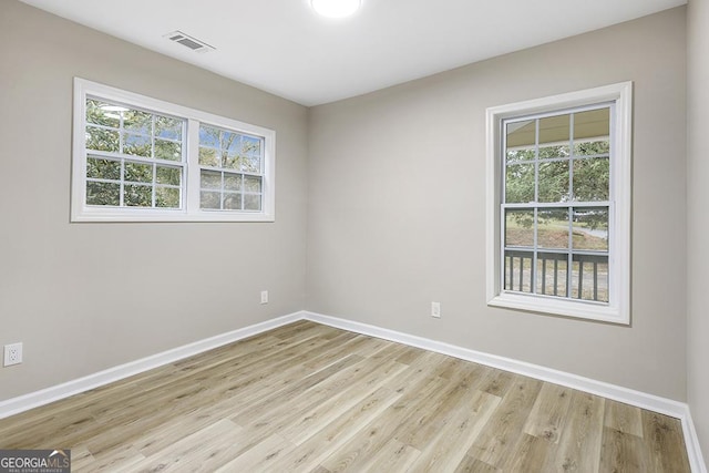 unfurnished room with visible vents, light wood finished floors, and baseboards