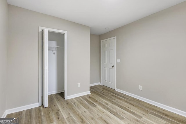 unfurnished bedroom featuring light wood finished floors, baseboards, and a closet