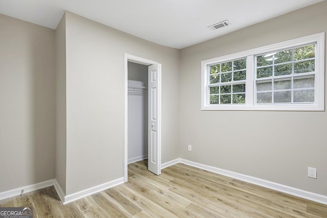 unfurnished bedroom featuring a closet, baseboards, visible vents, and light wood finished floors