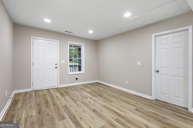 unfurnished room with light wood finished floors, baseboards, recessed lighting, and attic access
