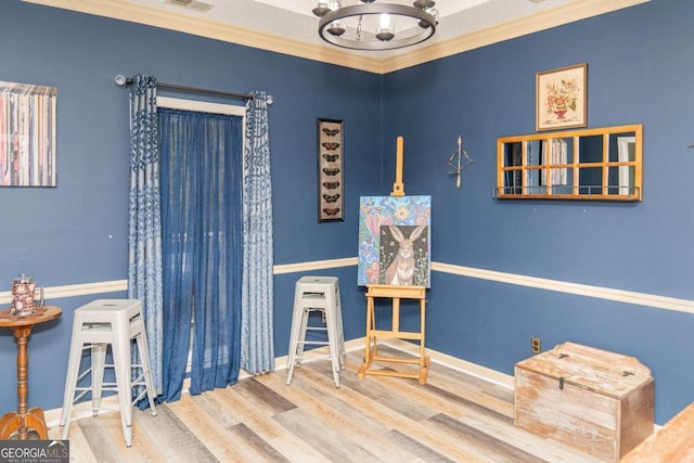 recreation room with hardwood / wood-style flooring, crown molding, and a chandelier