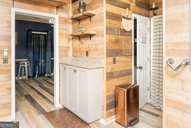 interior space featuring white cabinetry, light wood-type flooring, and wood walls