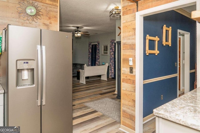 kitchen with ceiling fan, wood-type flooring, refrigerator with ice dispenser, and a textured ceiling