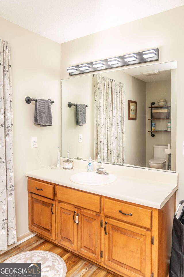 bathroom featuring hardwood / wood-style floors, shower / tub combo, a textured ceiling, and toilet