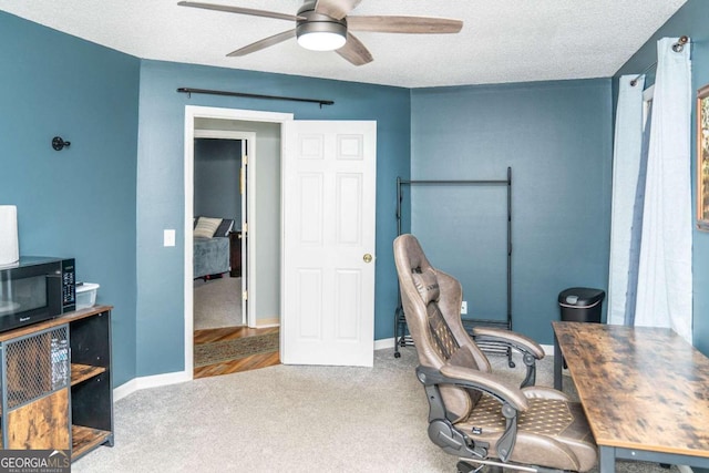 home office with ceiling fan, carpet flooring, and a textured ceiling