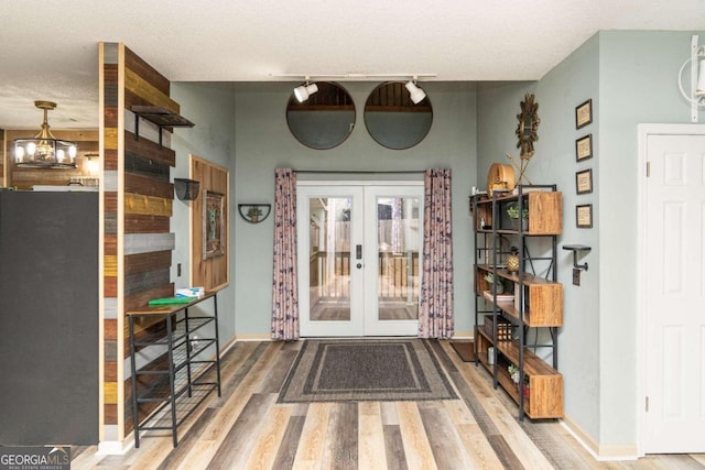 foyer entrance featuring french doors, a notable chandelier, and hardwood / wood-style flooring