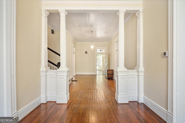 hall with dark wood-type flooring, decorative columns, and ornamental molding