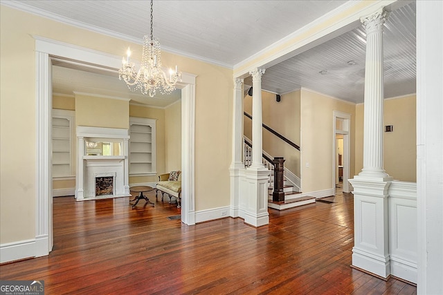 dining space featuring dark hardwood / wood-style flooring, a notable chandelier, decorative columns, crown molding, and built in features