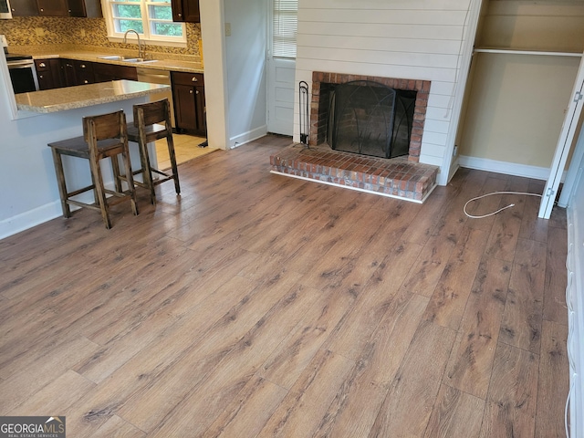 living room featuring a fireplace, sink, and light wood-type flooring