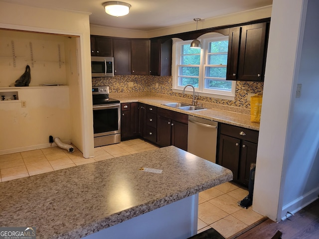 kitchen with backsplash, sink, decorative light fixtures, dark brown cabinets, and stainless steel appliances