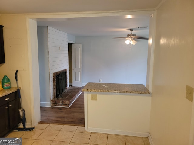 kitchen featuring ceiling fan, light hardwood / wood-style flooring, and a brick fireplace