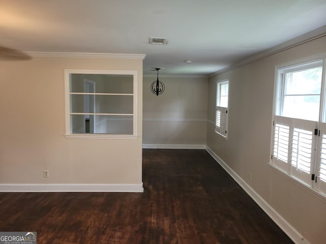 empty room featuring a chandelier, dark hardwood / wood-style flooring, and ornamental molding