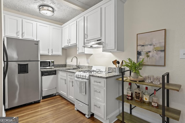 kitchen featuring sink, light stone counters, appliances with stainless steel finishes, a textured ceiling, and white cabinets