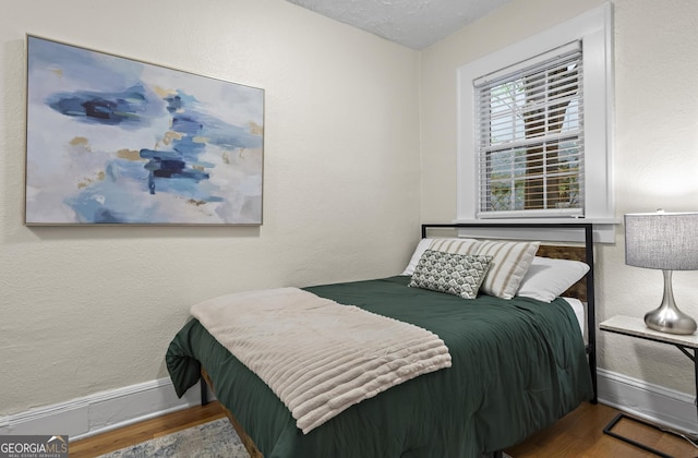 bedroom with a textured ceiling and hardwood / wood-style flooring