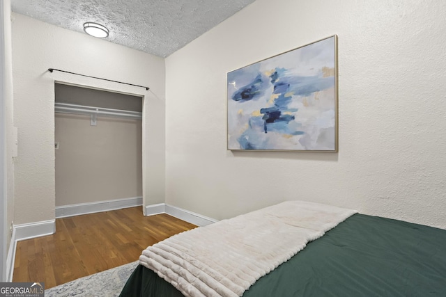 bedroom with hardwood / wood-style floors, a textured ceiling, and a closet