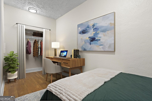 bedroom with wood-type flooring, a textured ceiling, and a closet