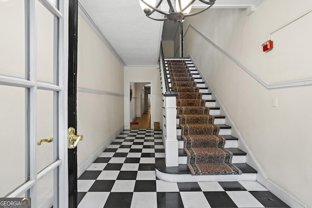 stairs featuring ornamental molding, a notable chandelier, and a textured ceiling