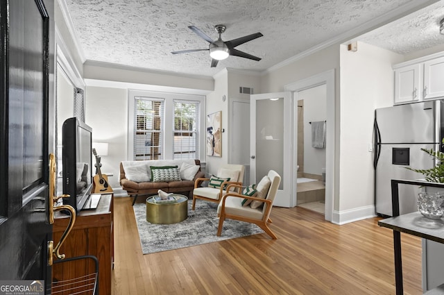 living room featuring ceiling fan, a textured ceiling, light hardwood / wood-style flooring, and crown molding