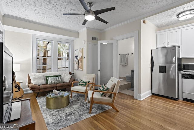 living room featuring ornamental molding, light wood-type flooring, a textured ceiling, and ceiling fan