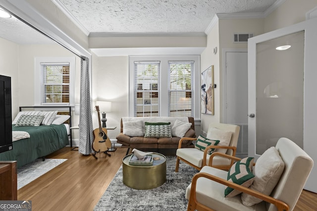 sitting room with a wealth of natural light, hardwood / wood-style floors, ornamental molding, and a textured ceiling