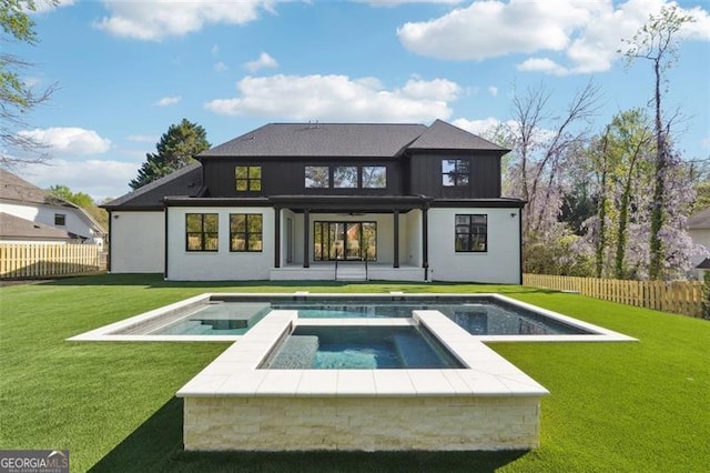 back of house featuring a yard and a swimming pool with hot tub