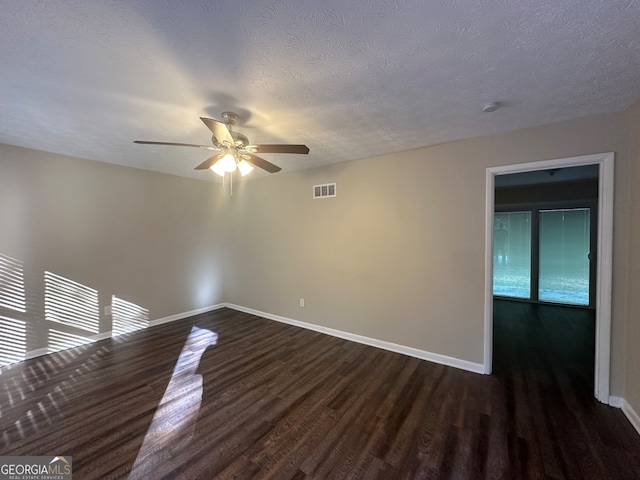 empty room with dark hardwood / wood-style flooring, a textured ceiling, and ceiling fan