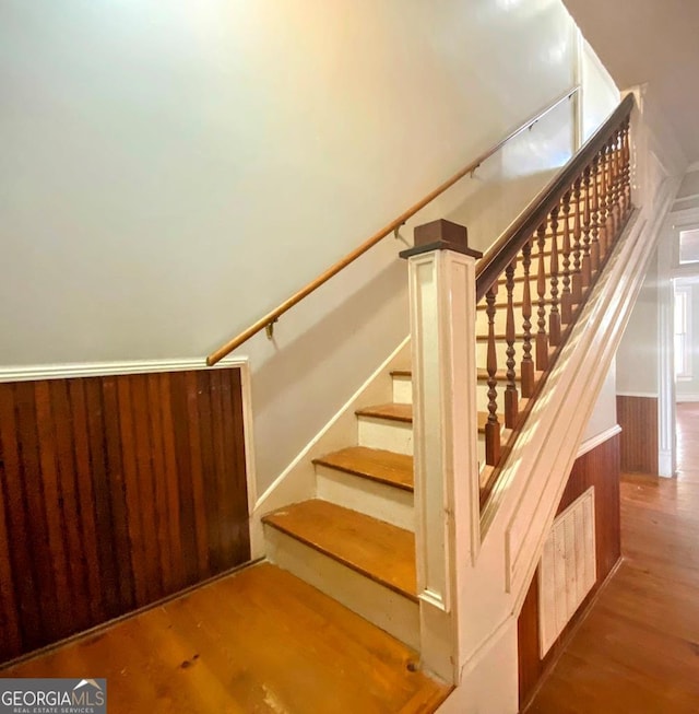 stairs with wood walls and wood-type flooring