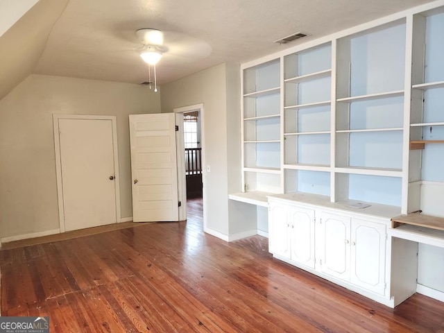 interior space with ceiling fan, built in desk, and wood-type flooring