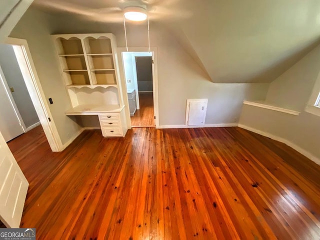 additional living space with dark hardwood / wood-style flooring, lofted ceiling, and built in features