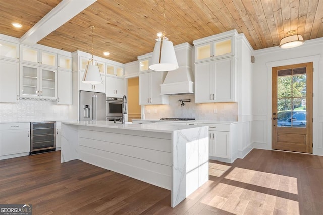 kitchen featuring dark hardwood / wood-style flooring, beverage cooler, white cabinets, an island with sink, and appliances with stainless steel finishes