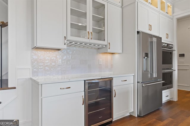 kitchen with dark wood-type flooring, beverage cooler, white cabinetry, and appliances with stainless steel finishes