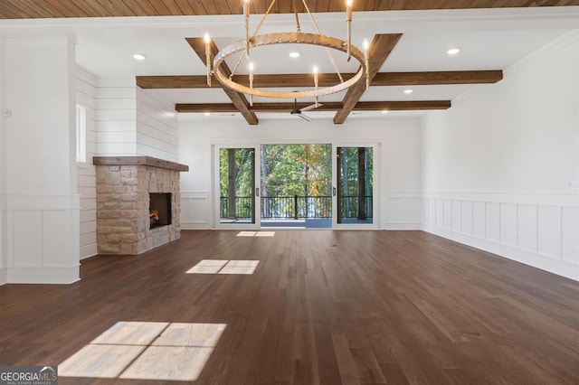 unfurnished living room with a stone fireplace, dark hardwood / wood-style flooring, a chandelier, ornamental molding, and beamed ceiling