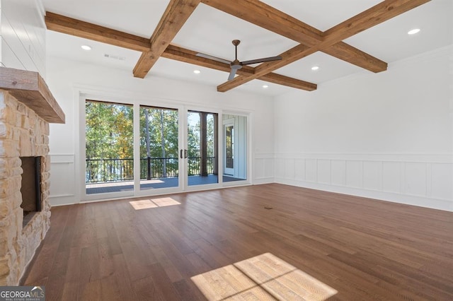 unfurnished living room featuring beamed ceiling, dark hardwood / wood-style floors, a stone fireplace, and coffered ceiling