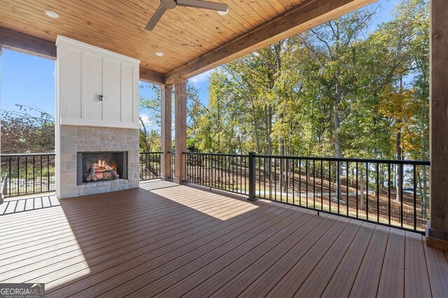 wooden terrace with ceiling fan and an outdoor stone fireplace