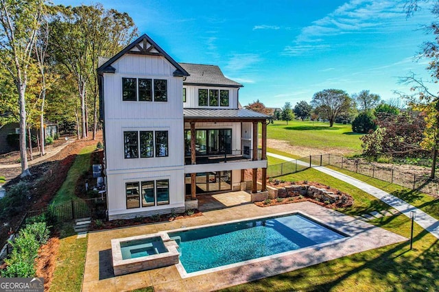 back of property featuring a pool with hot tub, a patio, a yard, and a balcony