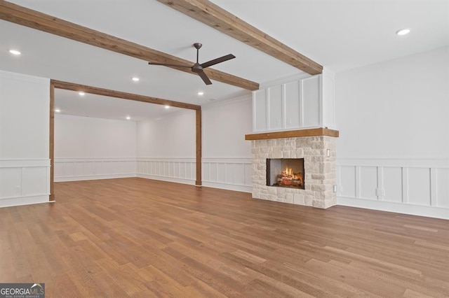 unfurnished living room with a fireplace, light hardwood / wood-style flooring, crown molding, and beam ceiling