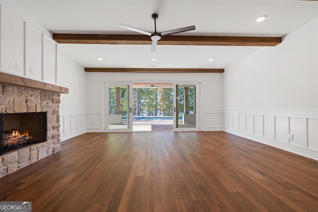 unfurnished living room with ornamental molding, a stone fireplace, beam ceiling, dark hardwood / wood-style flooring, and ceiling fan