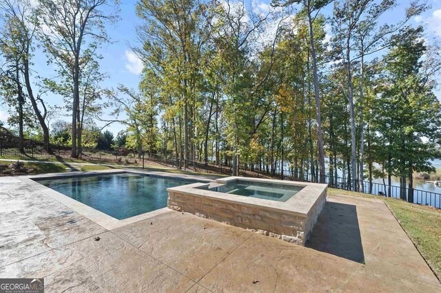 view of swimming pool featuring a water view, a patio, and an in ground hot tub