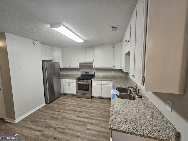 kitchen with visible vents, a sink, wood finished floors, appliances with stainless steel finishes, and white cabinets