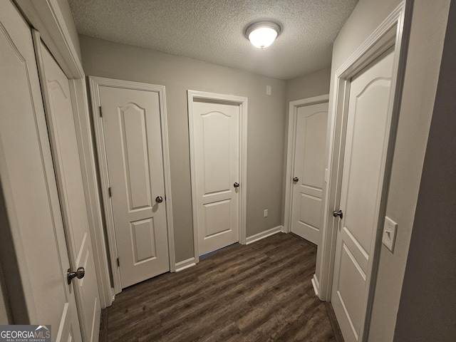 corridor with baseboards, a textured ceiling, and dark wood-style flooring