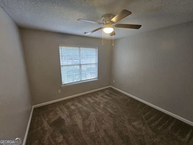 spare room featuring a ceiling fan, baseboards, dark colored carpet, and a textured ceiling