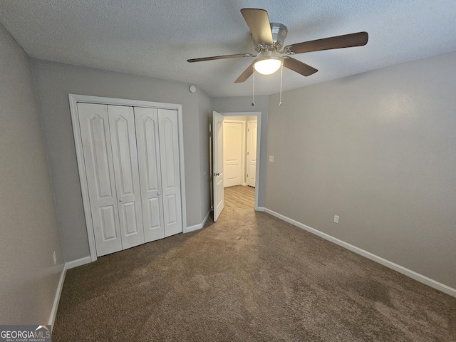 unfurnished bedroom featuring a closet, carpet floors, a textured ceiling, and baseboards