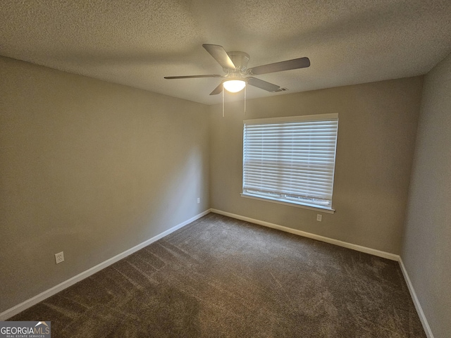 spare room with dark colored carpet, baseboards, a textured ceiling, and a ceiling fan