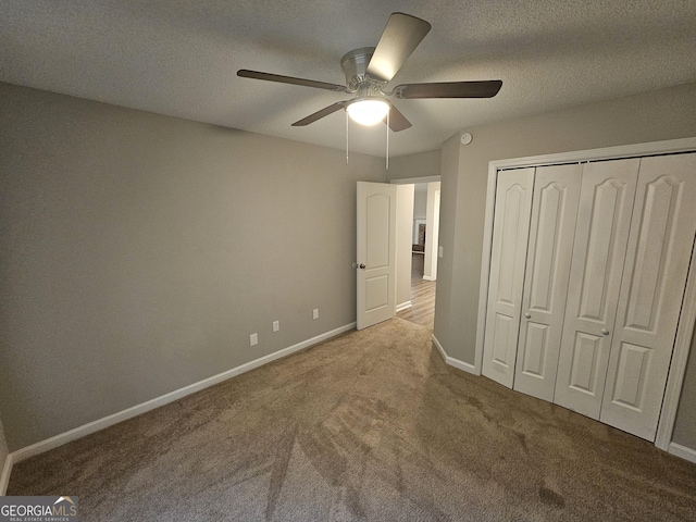 unfurnished bedroom featuring carpet, baseboards, ceiling fan, a closet, and a textured ceiling