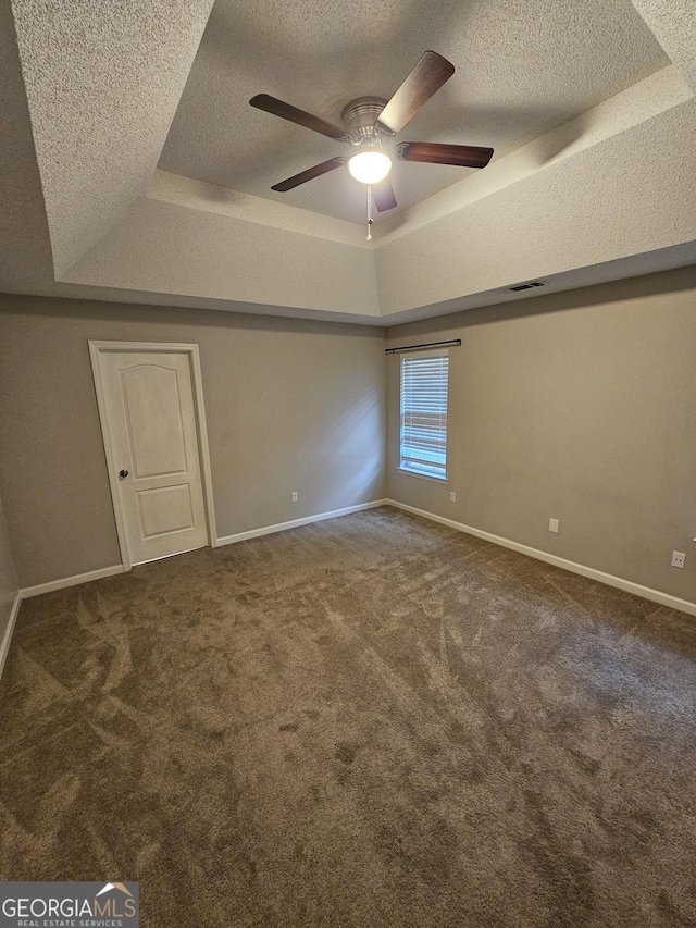 interior space with a textured ceiling, a raised ceiling, and carpet