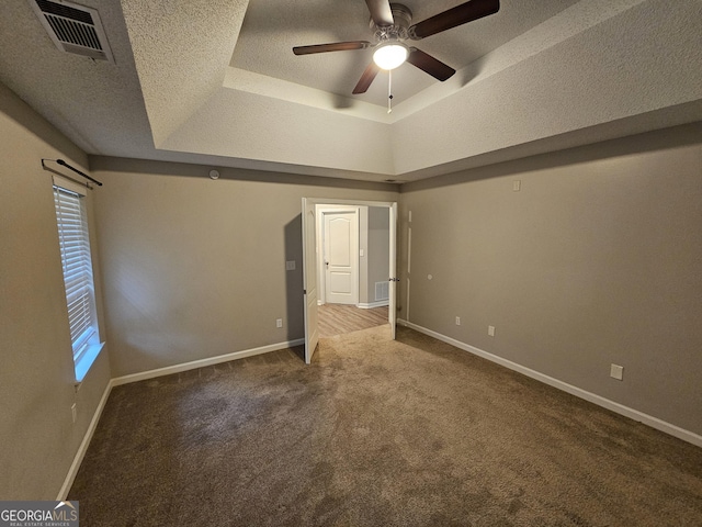 unfurnished bedroom with baseboards, visible vents, carpet floors, a textured ceiling, and a raised ceiling